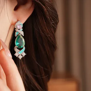 Close-up view of vintage palace style drop earrings with emerald green and pink zircons