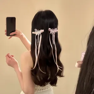 Gros plan sur des pinces à cheveux papillon roses à longs glands sur cheveux ondulés