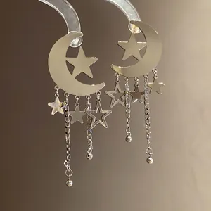 Macro detail of silver-colored crescent moon and star tassel drop earrings