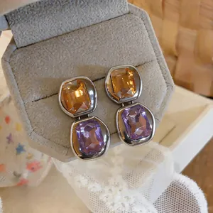 Detail shot of retro silver earrings with amber and purple rectangular faceted gemstones.