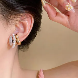 Elegant C-shaped earrings with pearls and pavé zircons shown in a detailed close-up view.