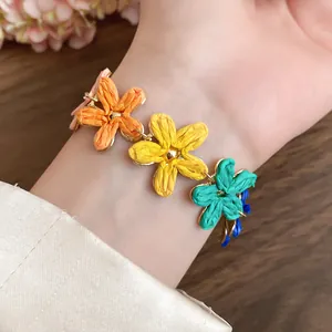 Detail of colorful raffia flower bracelet with woven petal charms in bohemian style.