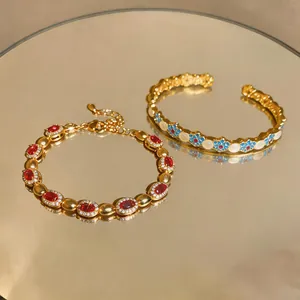 Primo piano dettagliato di bracciali vintage dorati con pietre rosse e motivi floreali blu