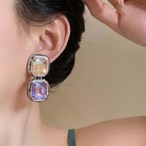 Close-up view of vintage-style square crystal drop earrings with champagne and purple gems