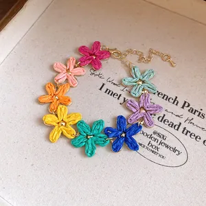 Macro view of bohemian multi-color raffia flower choker with adjustable gold chain