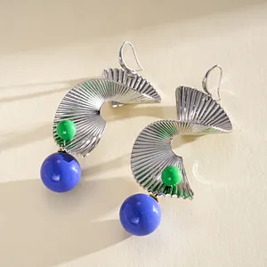 Detailansicht der silbernen Spirale-Ohrringe mit blauen Perlen und Metallstruktur