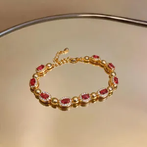 Vista dettagliata di un bracciale in oro vintage di lusso con pietre rosse ovali e cristalli
