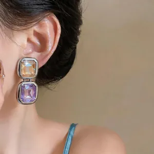 Detailed shot of French retro silver needle earrings with purple and amber crystals.
