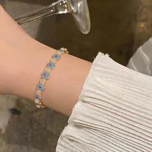 Primo piano di un braccialetto a fiori blu in stile vintage su un polso con manica bianca.
