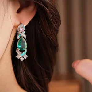 Macro detail of luxury palace style drop earrings featuring green zircon and blue enamel