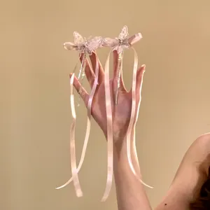 Détail de barrettes papillon roses avec de longs glands et rubans tenus à la main