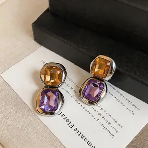 Close-up of elegant vintage square crystal stud earrings with amber and purple stones