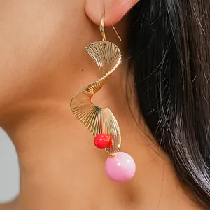 Detailansicht goldene Spiral-Ohrringe mit roten und rosa Perlen am Ohr getragen