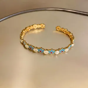 Vista macro dettagliata del bracciale vintage in oro con smalto blu e pietre bianche
