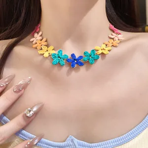 Close-up detail of bohemian colorful raffia flower necklace worn on model's collarbone
