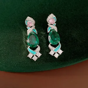 Detailed macro shot of vintage court style emerald green drop earrings with pink stones.