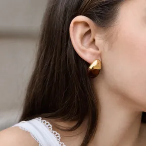 Close-up shot of elegant gold and brown resin teardrop earring on a female model's ear