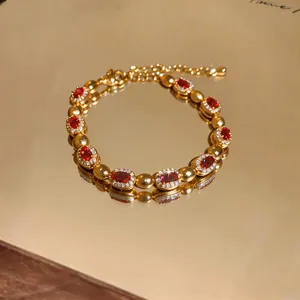Primo piano di un bracciale d'oro vintage con gemme rosse ovali e dettagli in zircone bianco