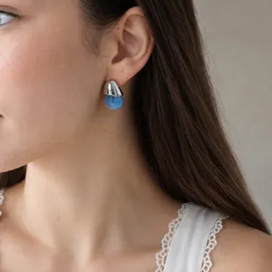 Close-up of a silver stainless steel and blue resin water drop earring on a model's ear