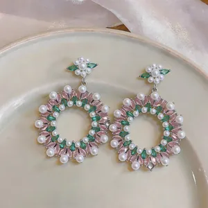 Macro detail of vintage pearl and colorful zircon wreath drop earrings on a ceramic plate
