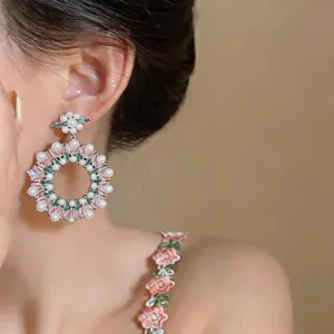 Close-up of retro floral hoop earrings with pink zircon and white pearls on model ear.