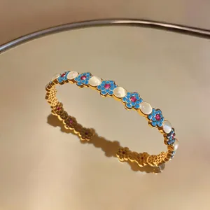 Vista dettagliata di un bracciale floreale vintage in oro con smalto blu e pietra di luna