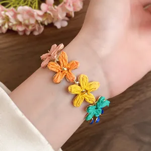 Close-up of colorful raffia flower bracelet on wrist with a soft floral background