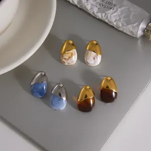 Close-up of stainless steel resin stud earrings in marbled and amber finishes.