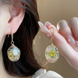 Close-up of elegant resin teardrop earrings featuring real dried flowers and gold wire