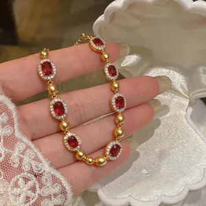 Dettaglio di un bracciale vintage dorato con pietre rosse e accenti di cristallo