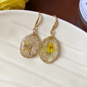 Elegant gold-toned wire-wrapped resin earrings with embedded yellow dried flowers.