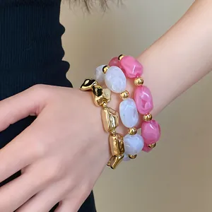 Close-up detail of irregular geometric acrylic elastic bracelets in pink and white.