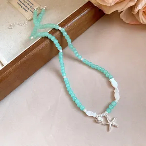 Détail d'un collier de perles turquoise avec étoile de mer pour les vacances d'été.