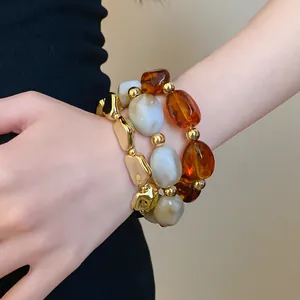 Detailed close-up view showing irregular amber and marbled acrylic beads on elastic bracelets