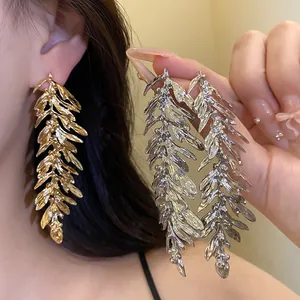 Detailed view of oversized gold and silver leaf feather tassel earrings for women