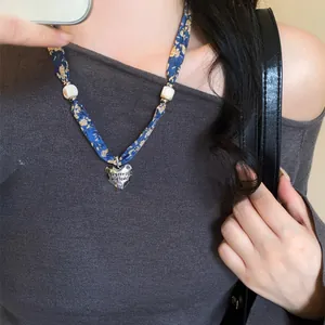 Vista dettagliata del pendente a cuore in argento su una collana a sciarpa in seta blu