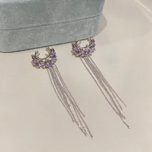 Close-up detail of purple stone ear cuffs with elegant long silver chain tassels.