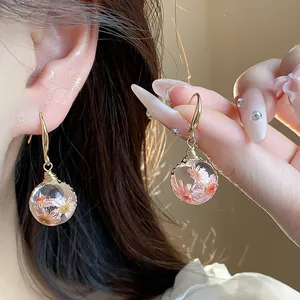 Detailed view of handmade resin ear hooks featuring delicate pink and white dried flowers