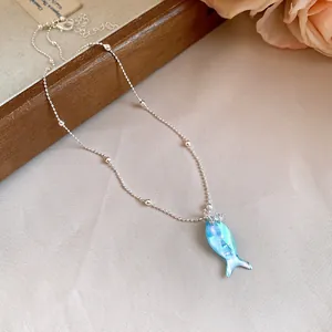 Vue détaillée d'un pendentif poisson bleu irisé sur un collier de perles en argent fin