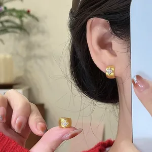 Close-up of 18k gold-plated zircon cross ear buckle earrings worn by an Asian woman