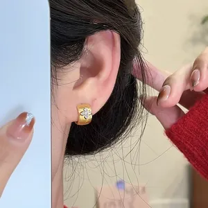 Close-up detail of elegant 18k gold-plated zircon cross ear buckle on model's ear