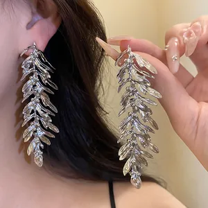 Close-up of large silver leaf tassel earrings showing intricate feather-like details.