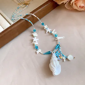 Gros plan d'un collier de perles artisanal thème océan avec pendentif conque et cristaux