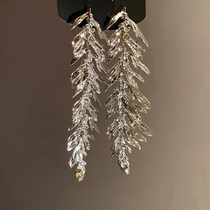 Detail view showing the intricate metallic leaf feather tassel design of silver earrings.