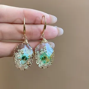 Close-up of resin waterdrop earrings with delicate real dried flowers inside