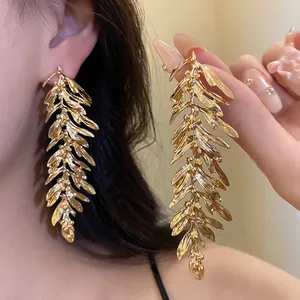 Close-up detail of golden leaf feather tassel earrings with a realistic metallic finish.