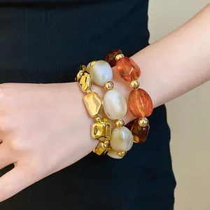 Close-up of vintage irregular geometric acrylic elastic bracelets with gold and amber beads.