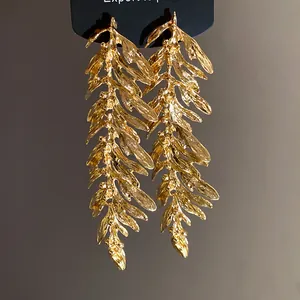 Detailed macro shot of elegant golden leaf branch tassel earrings with metallic texture
