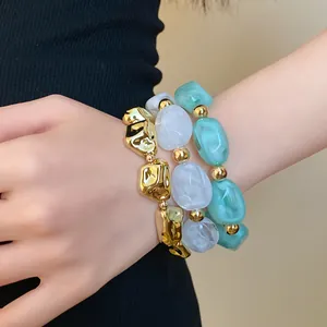 Close-up of three irregular geometric acrylic bracelets in gold, white, and mint green