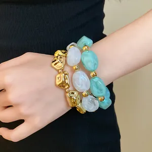 Close-up of irregular geometric acrylic elastic bracelets in gold, mint, and white.